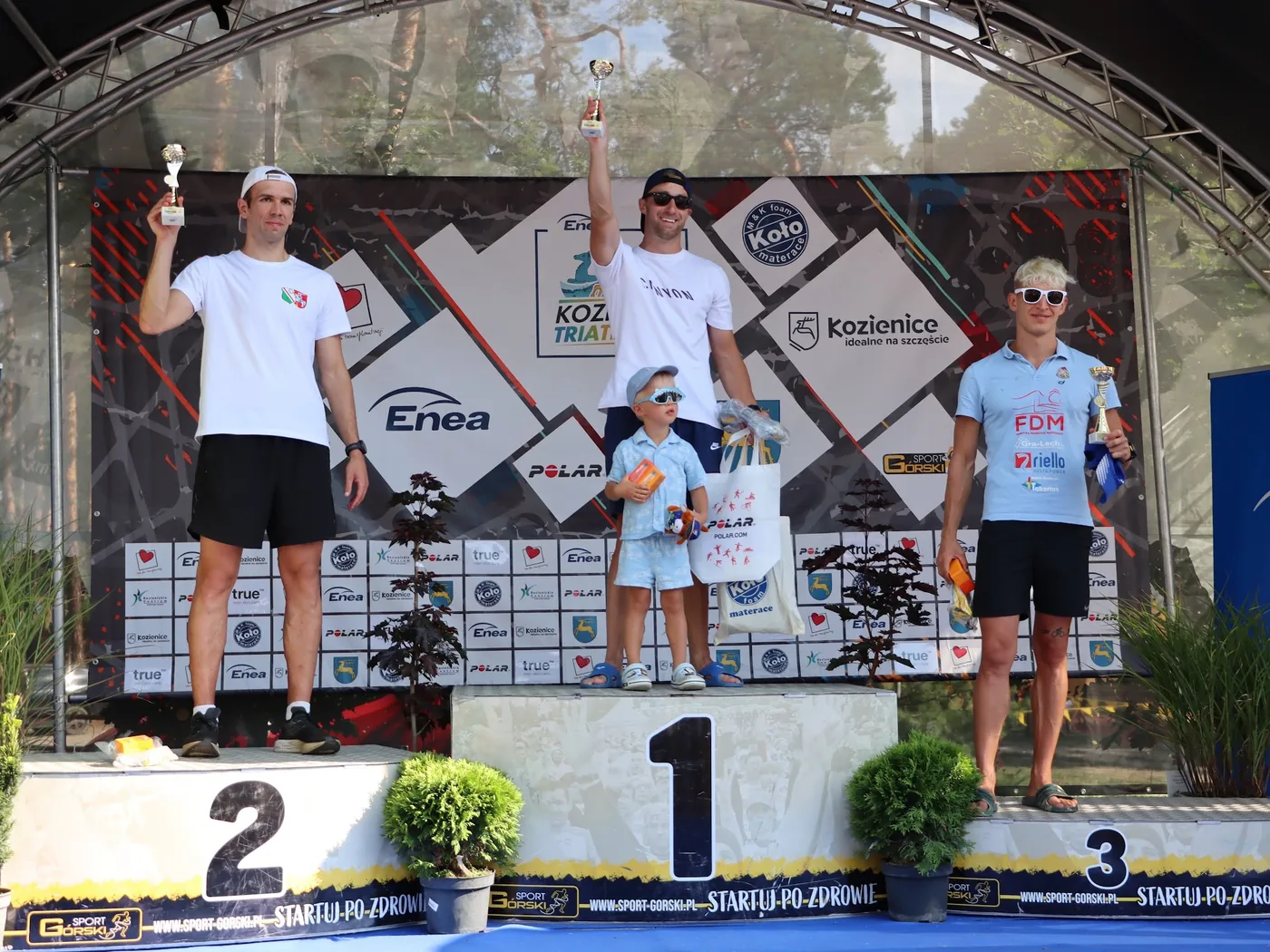 Dekoracja zwycięzców ENEA Kozienice Triathlon 2026 na podium z pucharami